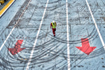 A man in a safety vest is walking across a parking lot