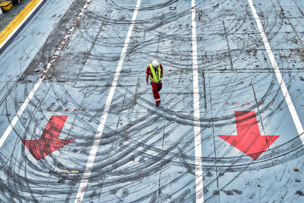 A man in a safety vest is walking across a parking lot