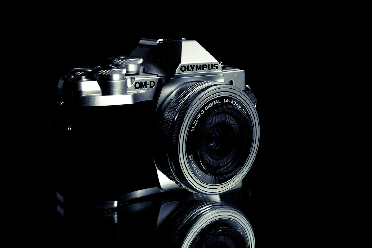 Silver olympus camera on a reflective black surface