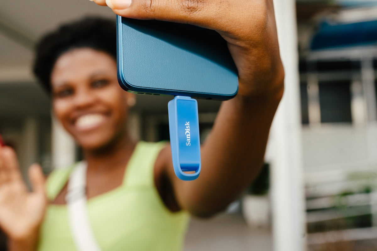Woman holding a smartphone with an attached sandisk usb drive.