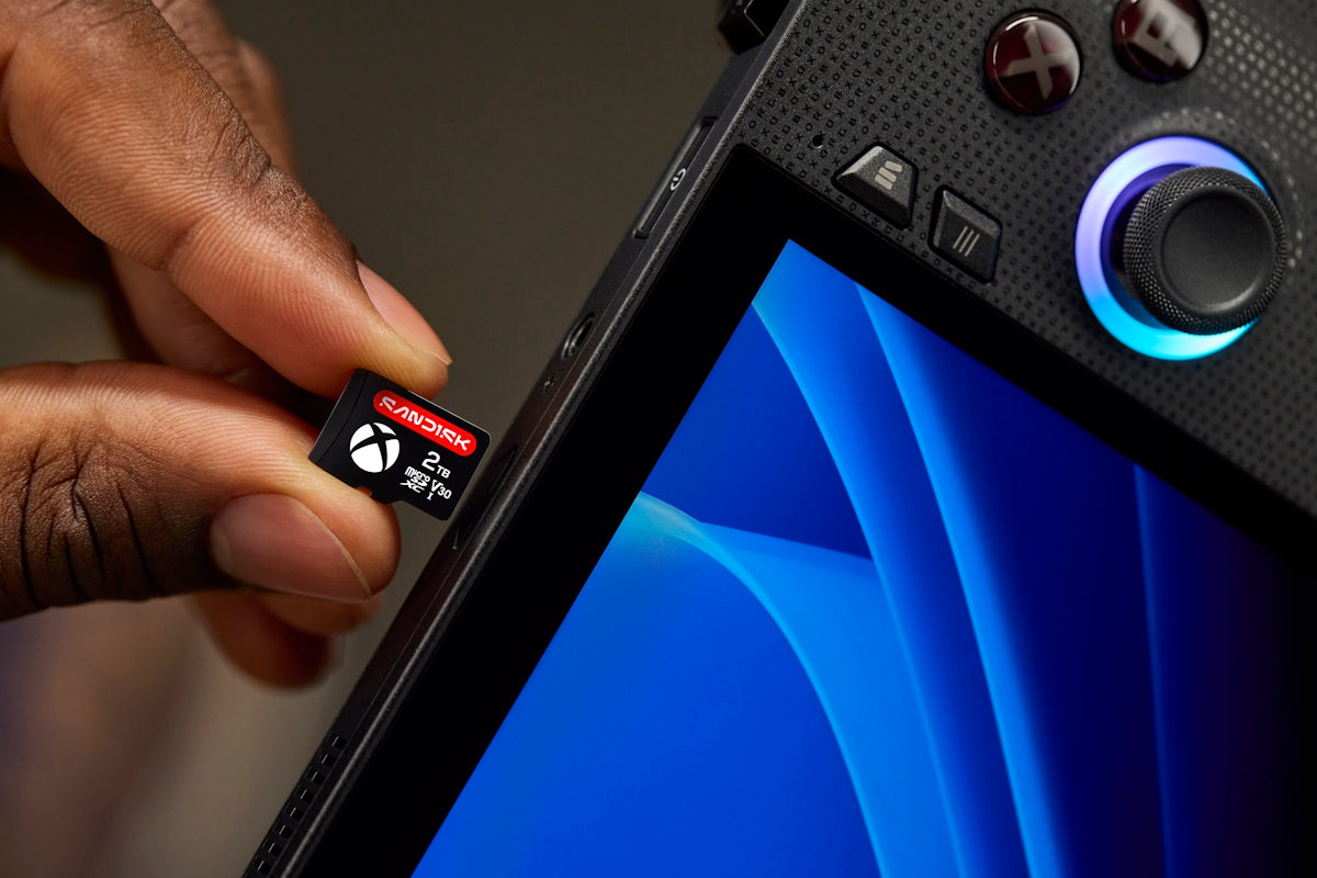 Hand inserting xbox memory card into portable gaming device.